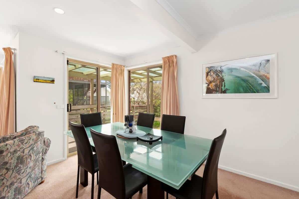A dining area with a glass table, black chairs, and a painting on the wall.