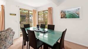 A dining area with a glass table, black chairs, and a painting on the wall.