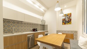 Une cuisine moderne avec des meubles en bois, un lave-vaisselle et un coin repas comprenant une table en bois et des chaises blanches.