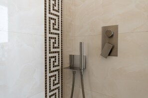 Uma casa de banho moderna com chuveiro, painel de controlo fixado na parede e um padrão decorativo em azulejos.