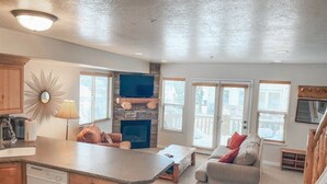 Un salon spacieux avec une cheminée, un coin repas et une cuisine dotée de meubles en bois.