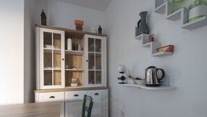 Une cuisine avec un meuble en bois, une bouilloire et une étagère ornée d’objets décoratifs.