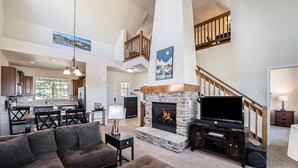 Un salón amplio con chimenea, una escalera y una zona de cocina.
