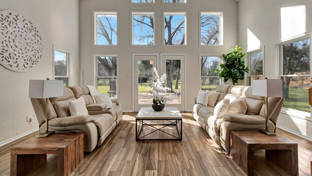 A spacious living room with two beige sofas, a coffee table, and a large window with multiple panes. - Luxury rental in Southlake on 1-Acre! (Southlake)