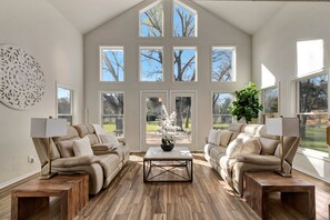 Un salon spacieux avec deux canapés beige, une table basse et une grande fenêtre à carreaux.