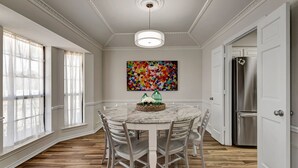 A dining room with a marble table, white chairs, a chandelier, and a colorful abstract painting on the wall. - Luxury rental in Southlake on 1-Acre! (Southlake)