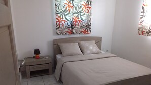 A bedroom with a bed, nightstand, lamp, and a wall with a floral pattern.