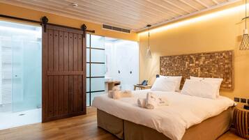 Un dormitorio moderno con una cama grande, piso de madera, puerta corrediza de vidrio y una original cabecera de madera.