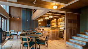 Ein Restaurant mit Holzböden, grünen Polstersesseln und einer Bar mit einer Treppe.