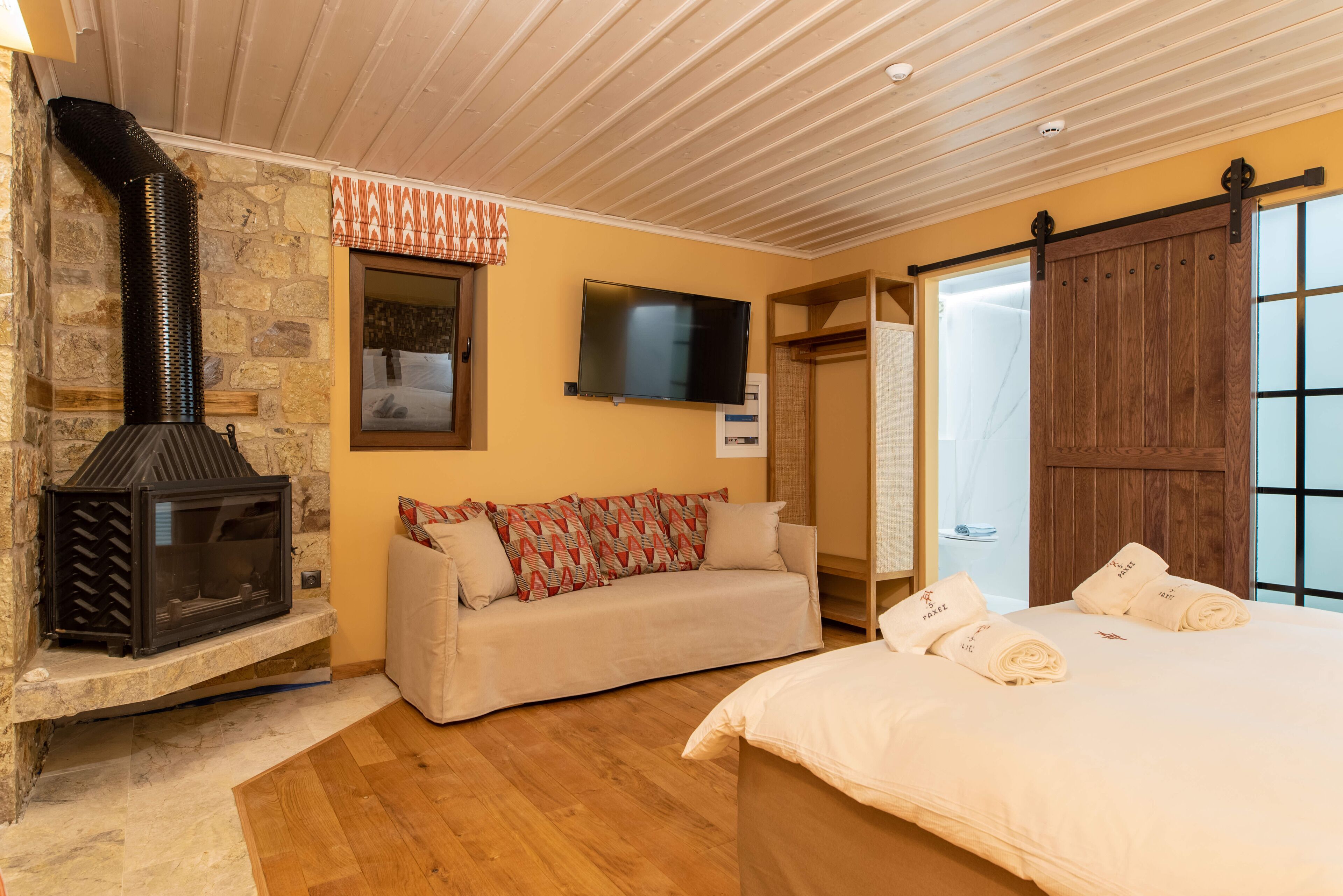 A cozy room with a stone fireplace, a sofa, a bed, and a sliding door.
