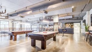 Un'ampia area interna con tavoli da biliardo, un bar e un soffitto alto con condotti a vista.