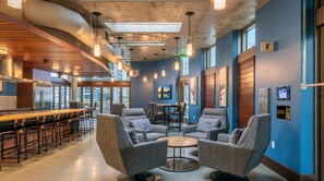 A modern lounge area with bar seating, comfortable sofas, and a central coffee table.