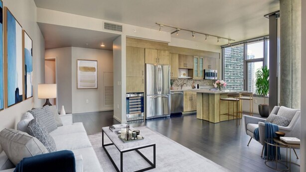 A modern kitchen with stainless steel appliances, a central island, and a view of the city through large windows. - Luxury Living: 2BR Condo at Via 6 (Seattle)