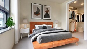 A modern bedroom with a bed, bedside tables, a closet, and artwork on the wall. - Luxury Living: 2BR Condo at Via 6 (Seattle)