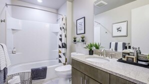 A modern bathroom with a shower, toilet, and vanity with two sinks. - Luxury Living: 2BR Condo at Via 6 (Seattle)