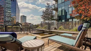 A rooftop terrace with lounge chairs, a small table, and a water feature.