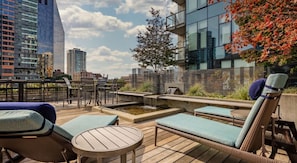 Une terrasse sur le toit, dotée de chaises longues, d’une petite table et d’un élément décoratif aquatique.