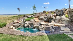 A landscaped outdoor area with a small pool, rock formations, and a waterfall. - Luxury Mansion Retreat, Sleeps 16+ ,Panoramic VIEWS 36 Acre Land .in the city . (Castle Rock)