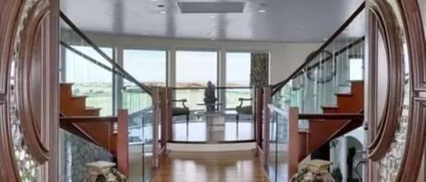 Un hall spacieux avec un plafond haut, un plancher en bois et un tapis décoratif placé au centre.