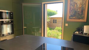 A kitchen with a built-in oven, a large window, and a painting on the wall. - Maison Contemporaine, Confortable et Lumineuse (Saint-Briac-sur-mer)