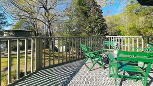 A covered outdoor patio with a patterned floor, green chairs, and a metal railing. - The Leia 2BR Bright Retreat by Velvet Ditch Villas (Oxford)