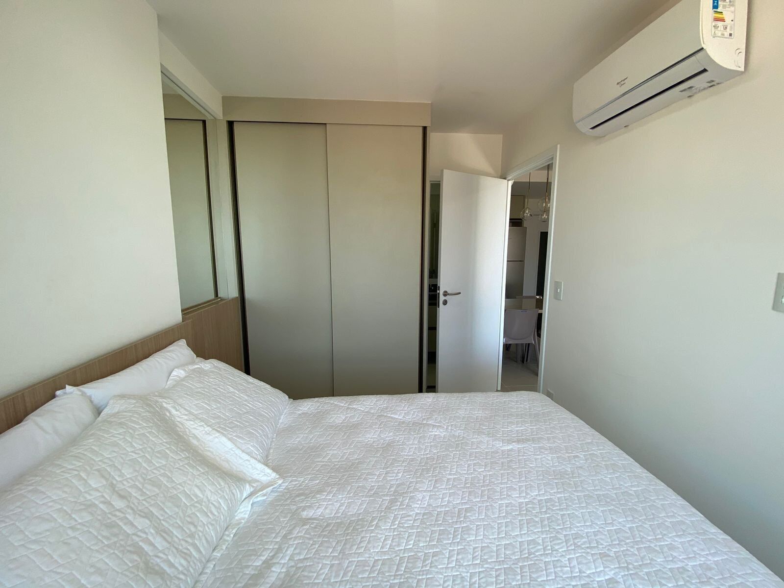 A bedroom with a bed, a wardrobe, and an air conditioning unit.