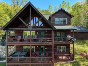 A two-story log cabin with multiple balconies, outdoor seating, and a stone wall. - Big Sky Overlook - Hottub- Firepit - Pool Table (Blairsville)