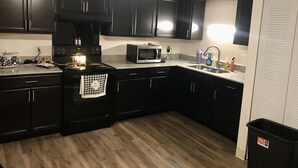 A kitchen with black cabinets, a microwave, a stove, and a sink. - Large Modern Smart House, voice controlled (Bloomington)