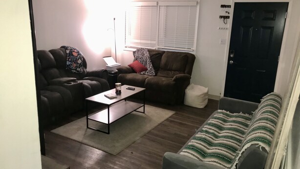 A living room with two sofas, a coffee table, a lamp, and a door.