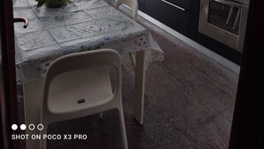 Une cuisine compacte comprenant une table à manger, des chaises, un évier, une cuisinière et des placards.
