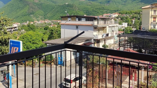 Un quartier résidentiel avec des maisons, une station-service et des montagnes en arrière-plan.