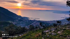 Un paysage urbain côtier avec un coucher de soleil sur la mer, présentant un mélange de paysages urbains et naturels.