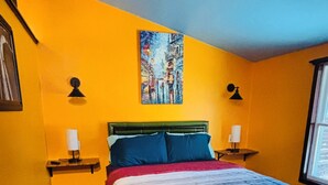 Un dormitorio con una cama, dos lámparas de noche, un cuadro en la pared y una ventana.