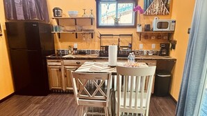 Una cocina compacta con comedor, armarios de madera, un refrigerador y un microondas.