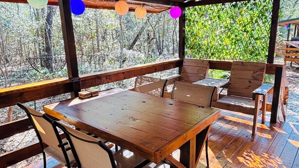 Una terraza de madera con una mesa y sillas, rodeada por una valla de madera y árboles.
