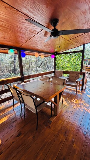A wooden deck with a table and chairs, surrounded by a wooden fence and trees. - Cabin Zancudo: a Hidden Gem! (Supply)