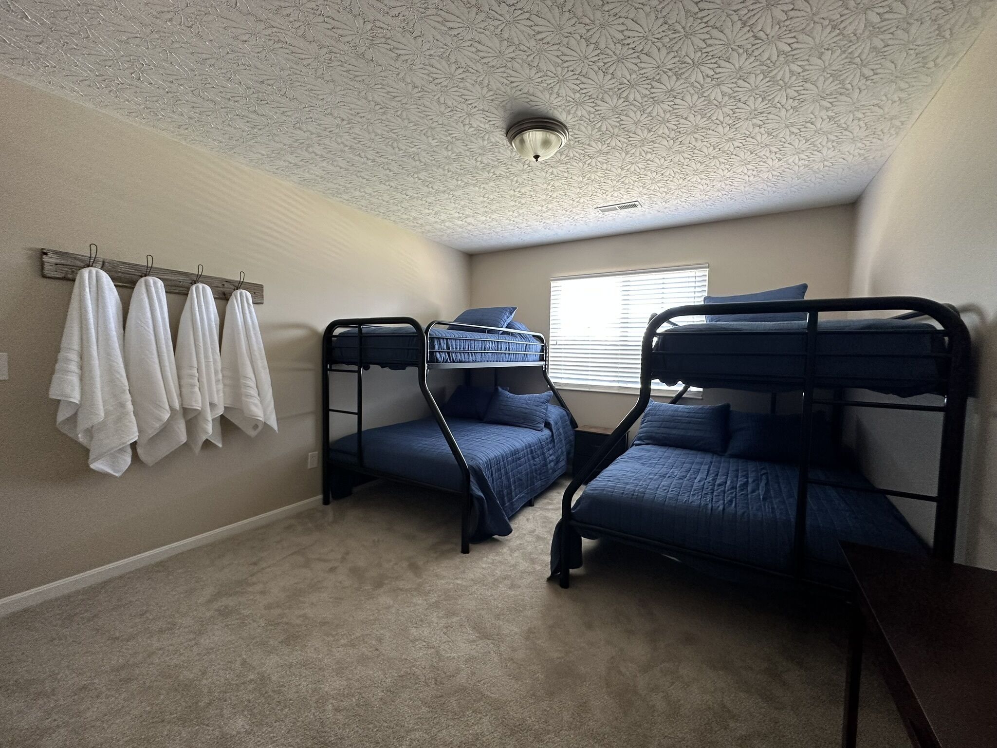 Une chambre avec des lits superposés, un plafond orné de motifs floraux et une fenêtre avec des stores.