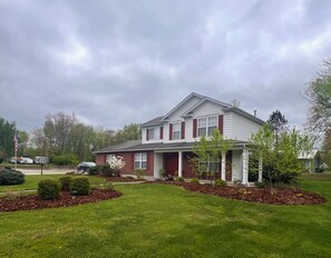 Une maison à deux étages avec un porche à l’avant, une allée et une pelouse bien entretenue.