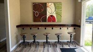 Una zona de bar con mostrador de madera y cinco taburetes.