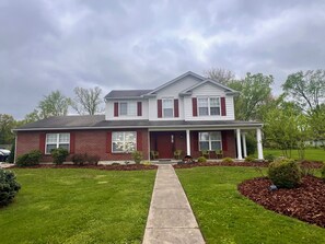 A two-story house with a front porch, a driveway, and a well-maintained lawn.