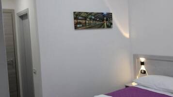 Una habitación con cama, un cuadro y una mesita de noche.
