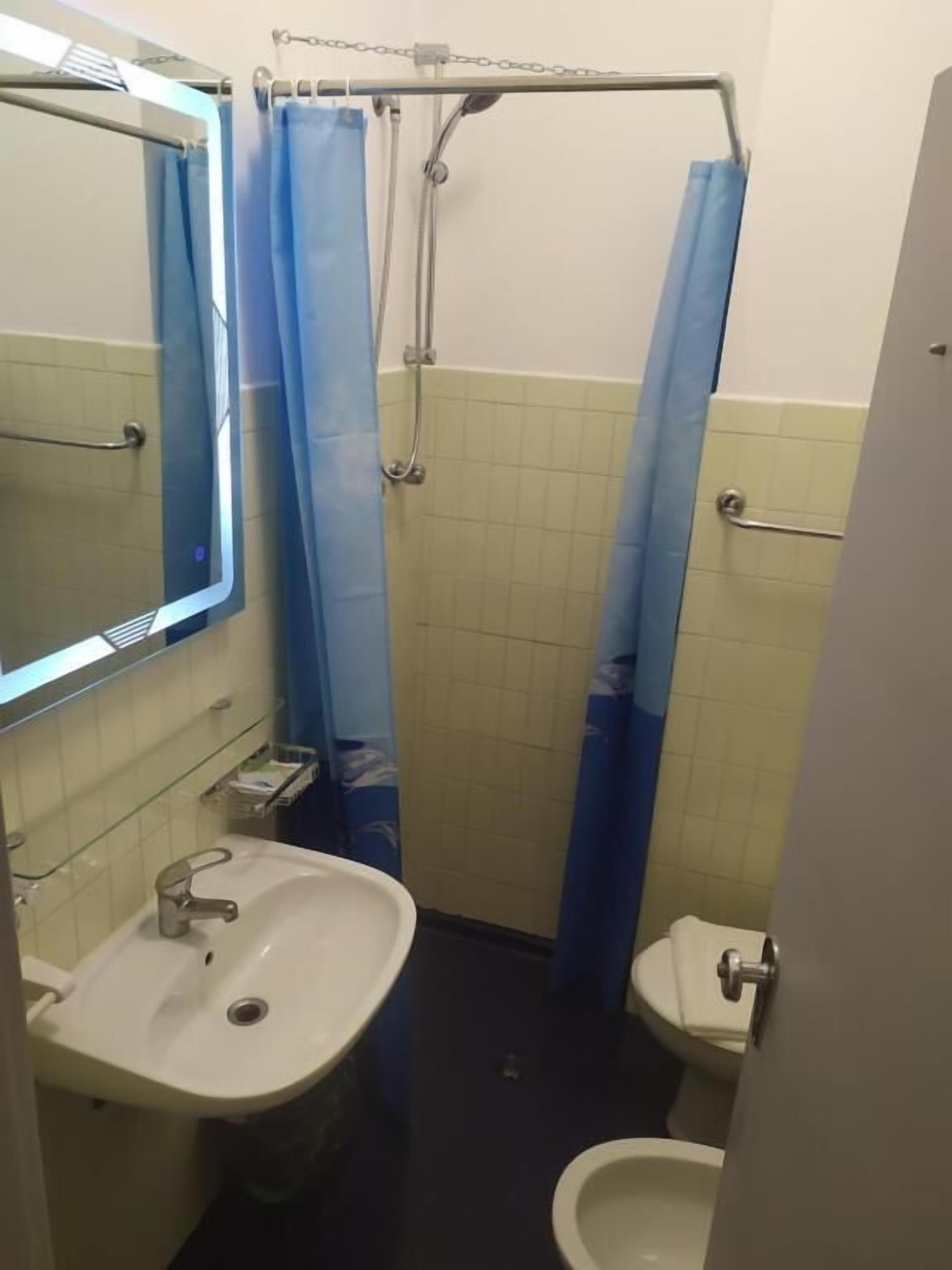 Un baño pequeño con lavamanos, inodoro y cortina de ducha.