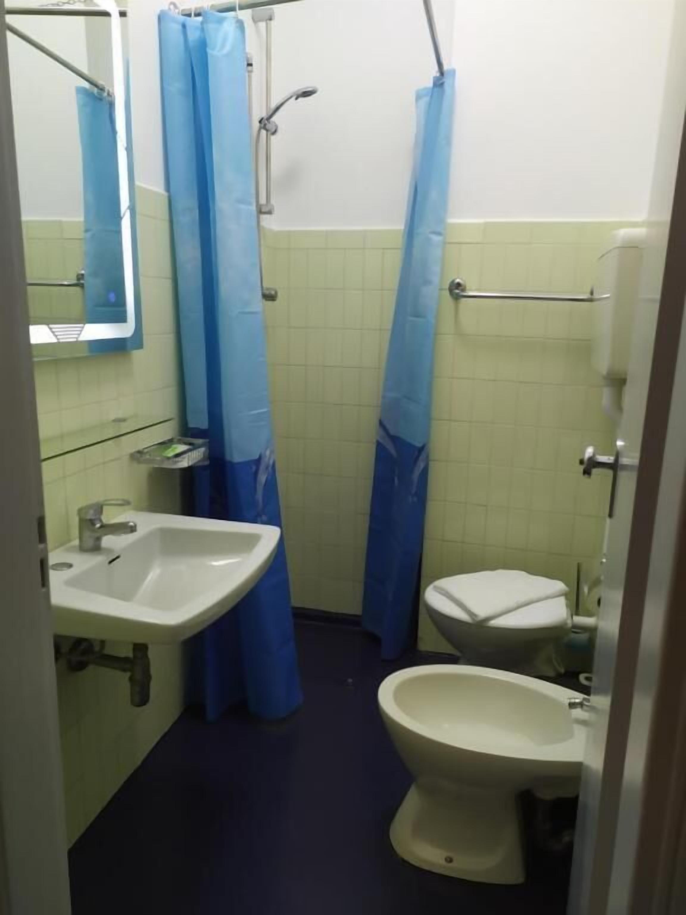 Un baño pequeño con lavamanos, inodoro y cortina de ducha.