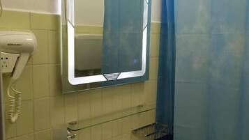 Un baño con un lavamanos blanco, un espejo, una cortina de ducha azul y un secador de manos.