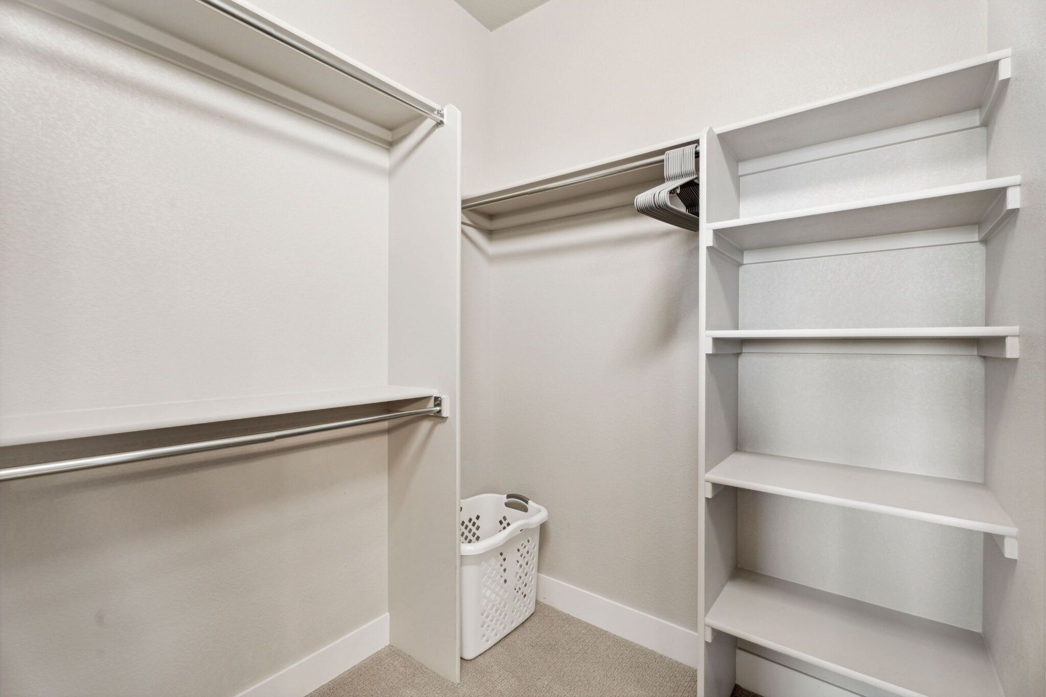 A walk-in closet with white shelving units and a hanging rod.