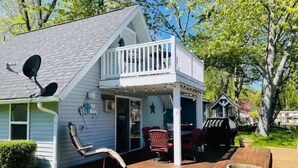 A two-story house with a covered porch, a satellite dish, and outdoor furniture. - Adorable Gun Lake Cottage (Shelbyville)