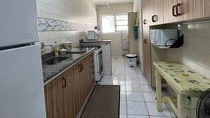 A compact kitchen with wooden cabinets, a refrigerator, a microwave, and a sink.