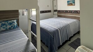 A room with two beds, a ceiling fan, an air conditioning unit, and a door with a mirror.