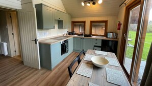 Une cuisine compacte dotée d’un îlot central, d’un plancher en bois et d’un coin repas agrémenté d’un grand saladier et de sets de table.