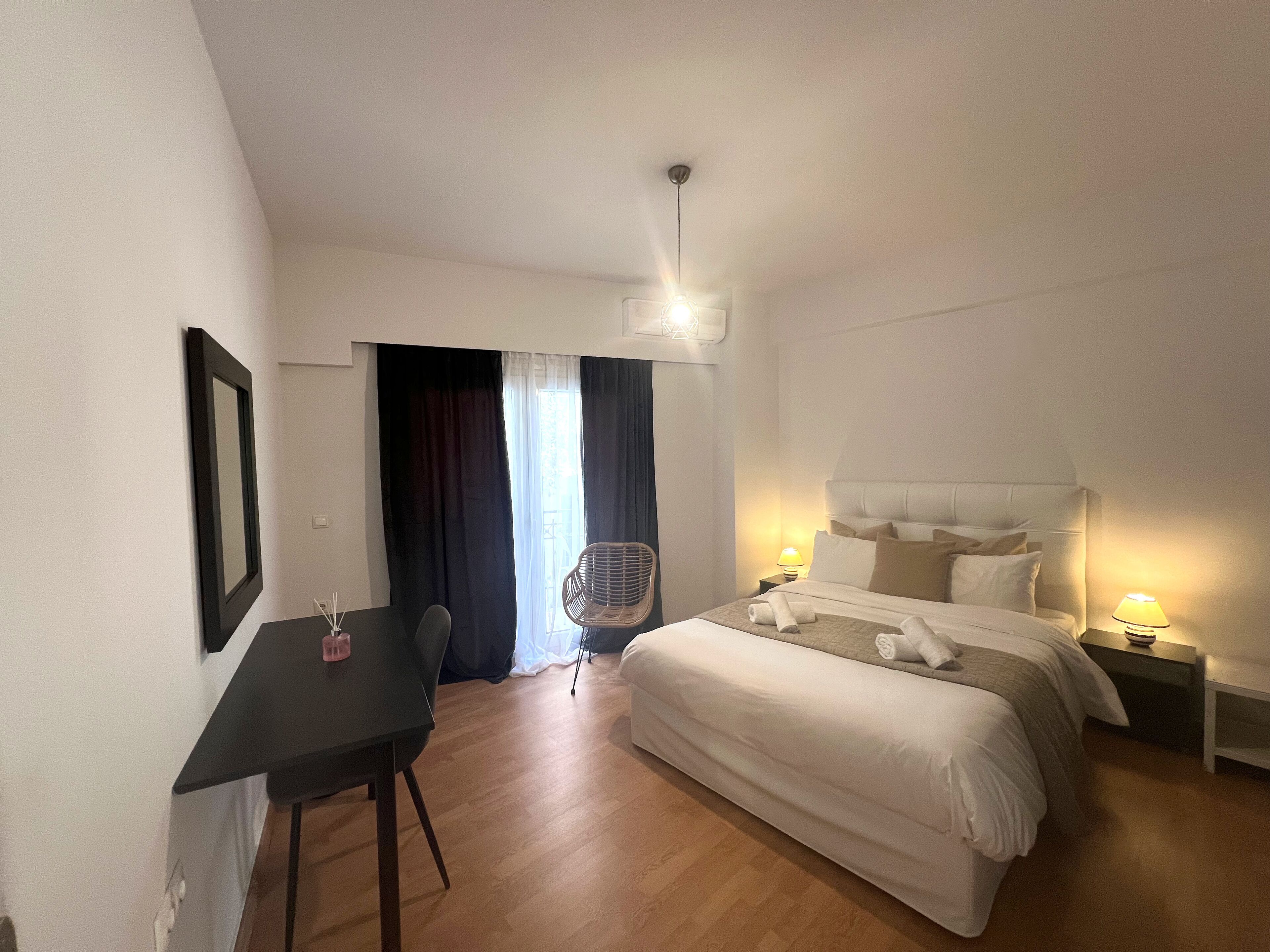 Hotellihuone, jossa on sänky, yöpöytä, tuoli ja työpöytä.
